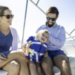 Beautiful multiracial young family with daughter enjoying a day on the water boating